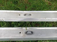 Photo showing two metal door trim pieces lying on grass with clearly visible 'Body by Fisher' emblems, one emblem fading.