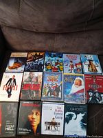 Photo showing 14 DVD cases placed on a couch, titles include Forrest Gump, From Hell, The Shawshank Redemption, Hitch, Ghost, and others.