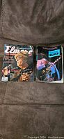 Both magazine and book laid side by side on a brown fabric surface. Magazine cover features musician and visible creasing. Book cover shows a guitar player in blues setting.