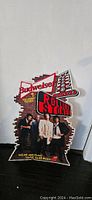 Photo showing a shaped tin sign with Budweiser and Rolling Stones branding and a photo of the band members.