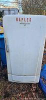 Closed front view of white Coldspot refrigerator with 'NAPLES' text and handle, showing overall condition and rust spots.