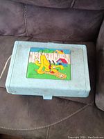 Closed vintage Pluto record player in suitcase style with blue textured outer case and Pluto cartoon image on top.