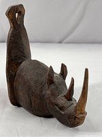 Front angled view of the hand carved wooden rhinoceros showing texture details and three horns.