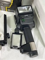 Close-up of Sunpak Auto 522 Thyristor electronic flash unit showing the flash head, textured handle, and mounting bracket attachment.