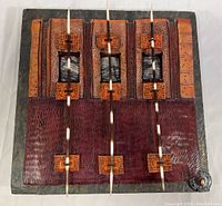 Front view of signed ceramic art wall sculpture showing multi-layered plates, earth toned colors, three vertical porcupine quills passing through ceramic square mounts.