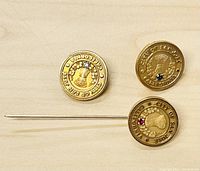 Three round vintage yellow gold filled service pins displayed flat on a light wood surface. Each features an inset stone and embossed text around the edge.
