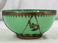 Side view of the vintage green glass temple bowl showcasing the sawtooth silver rim and one dragon emblem on the silver band.