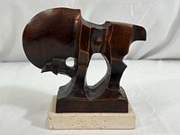 Front view of abstract bronze horse figure on travertine base