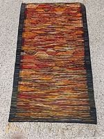 Full view of the woven area rug laid flat on floor showing entire pattern and tassels at one end.