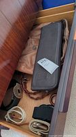 Drawer with belts rolled and folded next to handbags, showing various textures and belt styles
