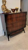 Front view of four drawer cherry veneer dresser with mid-century modern legs