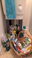 Lot contents viewed from an angle showing many bottles of household cleaners and personal care products along with two wicker baskets with handles.