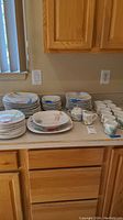 Full view of the dish set including multiple stacks of dishes and cups on a kitchen counter.