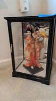 Front view of the black wooden and glass display case housing the vintage Japanese doll in kimono.
