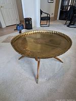 Full view of circular coffee table showing brass top and wooden base