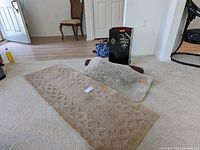 Photo of the carpet runner, bath mat, Asian style storage basket, and draft stoppers on light carpeted floor near a door.