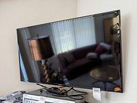 Samsung 40-inch LED TV turned off with remote control and wall mount on a table next to it.