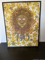 Framed poster showing the lion illustration with 'Leo' text underneath, yellow flower background, poster sized about 30x23 inches.