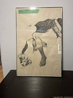 Full view of framed large nude sketch in charcoal or graphite showing crouched figure holding flowers on beige paper.