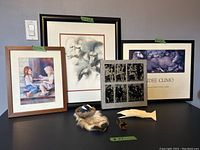 Framed art prints and sculptures arranged on a table, showing the variety of art pieces in the lot.