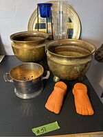 Photo showing brass plant holders, metal strainer, terracotta feet, patio glasses, tealight holder, large platter
