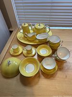 Overhead view showing all pieces including coffee pot, teapot, creamer, sugar bowl, lid, cups, saucers, bowls and platter