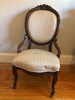 Front view of antique gentleman's chair showing upholstered seat and back with carved wooden frame and cabriole legs.