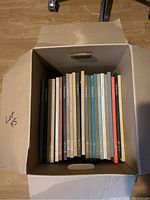 Open box showing 23 hardcover Horizon art books with multi-colored spines, stacked vertically in a cardboard box.