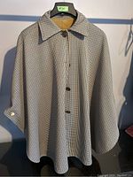 Front view of reversible cape on hanger showing houndstooth pattern