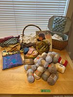 Overview of yarn balls, fabric remnants, sewing basket, and knitting basket with pattern book on table