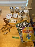 Photo of ceramic toothbrush holders, small dishes, carved wooden animals, Guinness World Records 2022 book, and Kids Charades game.