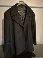 Front view of vintage US Navy wool pea coat size XXL, black color, double-breasted style with visible collar and buttons.