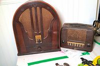 Overview photo showing both radios side by side on a table, Philco is larger cathedral style, Emerson smaller with faux leather texture