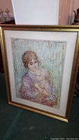 Frontal view of the framed print by Edna Hibel showing a mother and child in a tender pose, with visible matting and gold frame.