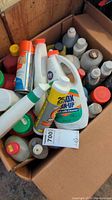 Box of assorted cleaning products including spray bottles, pour bottles and cans.