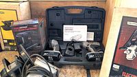 Photo showing the cordless drill/driver in open carrying case with batteries, charger, and manual, along with boxed 1/3 sheet pad sander, disc sander, and boxed electric planer.