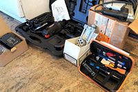 Full view of tools and accessories including Craftsman cutter in case, corded sabre saw, doweling jig box, soldering iron kit, and batteries.