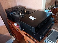 Overview of four stacked black audio components on wooden cabinet