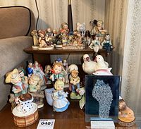 Overall view of 7 figurines displayed on two-tiered wooden stand near beige couch.