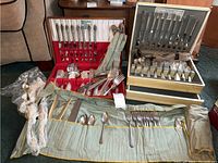 Wide view of the flatware sets displayed, showing forks, knives, spoons in wooden cases and fabric roll case.