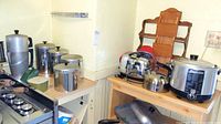 Multiple items displayed on two countertops, including moka pot, stainless steel canisters, Imperia pasta machine, toaster, teakettle and electric deep fryer