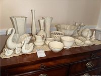 Full layout of Lenox white porcelain serving dishes, vases, butterfly bowls, candle holders, and matching sugar and cream dishes on wooden surface with lace doily
