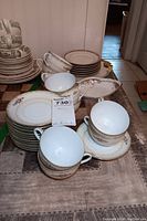 Image showing stacks of plates, sets of cups and saucers, and serving bowls. All are fine china with floral designs and gold trim.