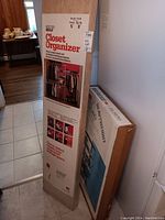 Boxed closet organizer system and boxed steel shelving unit leaning against a wall.