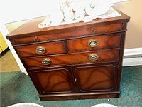 Front view of wood sideboard cabinet showing four drawers and two cabinet doors with brass handles.