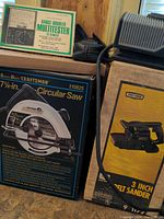 Photo showing boxed Craftsman 7 1/4 inch circular saw, boxed Craftsman 3 inch belt sander, and boxed Micronta multitester with text details visible.