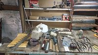 Wide shot of tools including shears, hand tools, levels, files, stapler, and other hardware on a workbench surface.