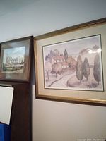 Two large framed prints displayed leaning against a wall, showing the cityscape on the left and the country scene on the right.
