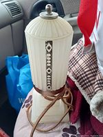 Front side view of white milk glass Art Deco vanity lamp with black accent and cloth wrapped cord showing overall design and condition