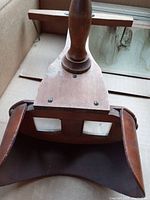 Close-up photo of wooden stereoscope showing handle and dual eyepieces, demonstrating the design and condition of wood and lenses.